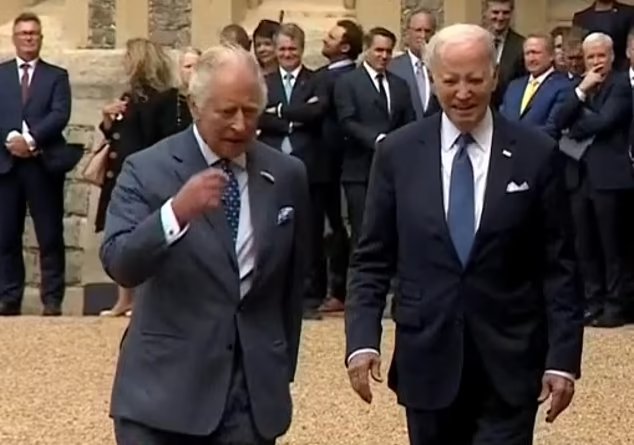 King Charles and Mr Biden chat together as officials look on at Windsor Castle today