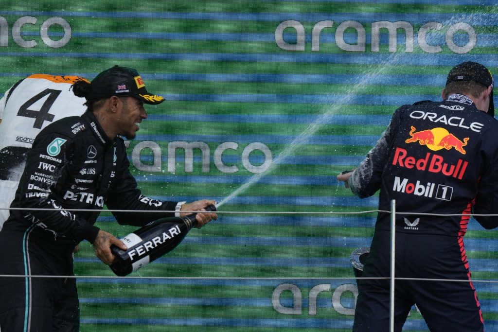 Third placed Mercedes driver Lewis Hamilton of Britain sprays champagne on winner Red Bull driver Max Verstappen
